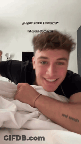 A Young Man Laying On A Bed With A Tattoo On His Arm GIF