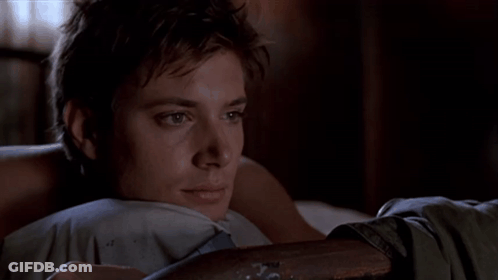 A Young Man Laying On A Bed With His Head Resting On A Pillow GIF