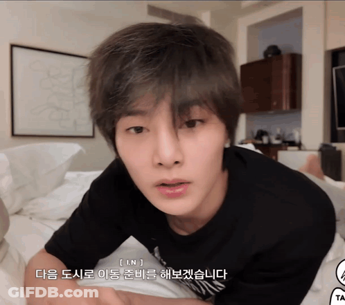 A Young Man Laying On A Bed With Korean Writing On The Bottom Of His Face GIF