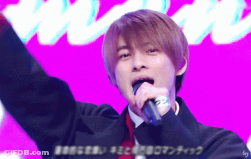 A Young Man Singing Into A Microphone With A Purple Background GIF
