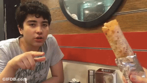 A Young Man Sitting At A Table With A Can Of Soda In Front Of Him And A Sandwich In Front Of Him GIF
