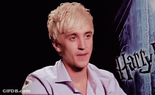 A Young Man Sitting In Front Of A Harry Potter Sign GIF