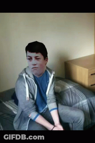 A Young Man Sitting On A Bed With A Picture Of His Face On His Chest GIF