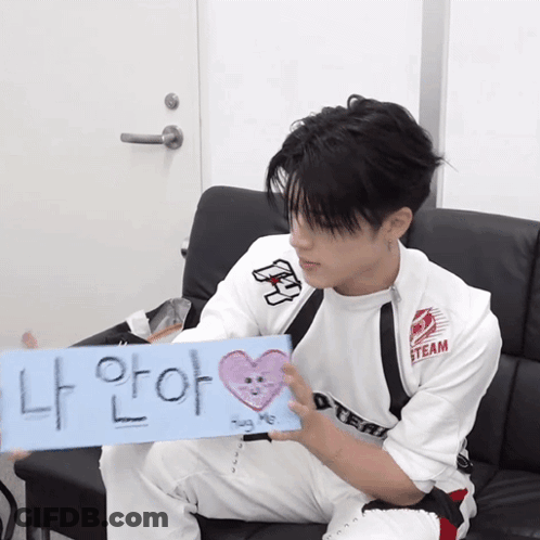 A Young Man Sitting On A Couch Holding A Sign That Says Steam GIF