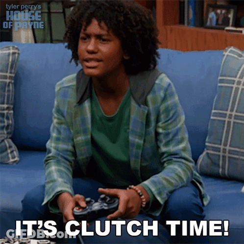 A Young Man Sitting On A Couch Playing A Video Game With The Words It 'S Clutch Time Below Him GIF