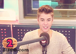 A Young Man Stands In Front Of A Microphone With The Number 2 On A Nut GIF