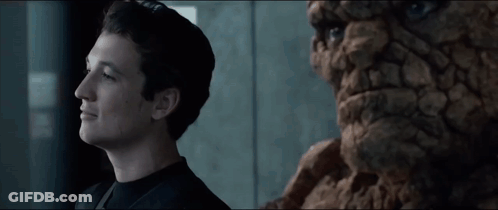 A Young Man Stands Next To A Statue Of A Man GIF