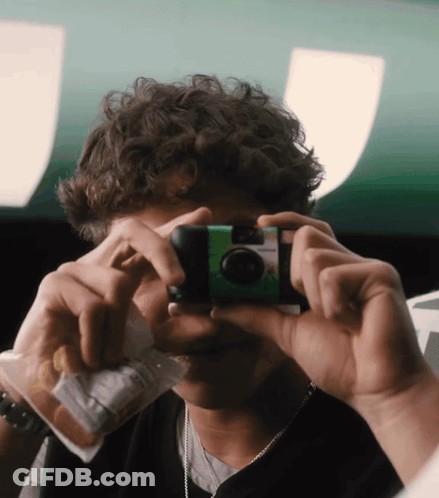 A Young Man Taking A Picture With A Green Camera GIF