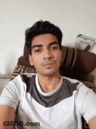 A Young Man Taking A Selfie In Front Of A Couch With A Magazine On It That Says ' Day ' On It GIF