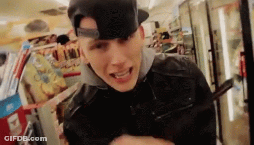 A Young Man Wearing A Baseball Cap And A Leather Jacket Is Standing In A Store . GIF