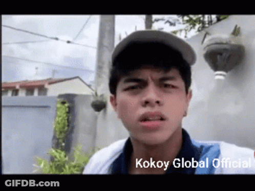 A Young Man Wearing A Baseball Cap Is Making A Funny Face With The Words Kokoy Global Official Written Below Him GIF
