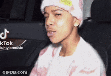 A Young Man Wearing A Beanie And A Sweater Is Sitting In A Car . GIF