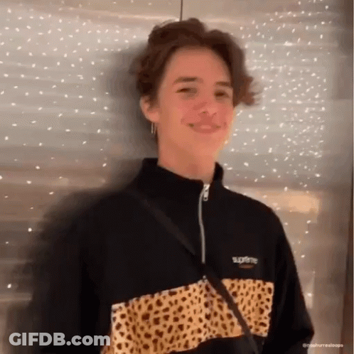 A Young Man Wearing A Black And Leopard Print Supreme Jacket Is Smiling . GIF