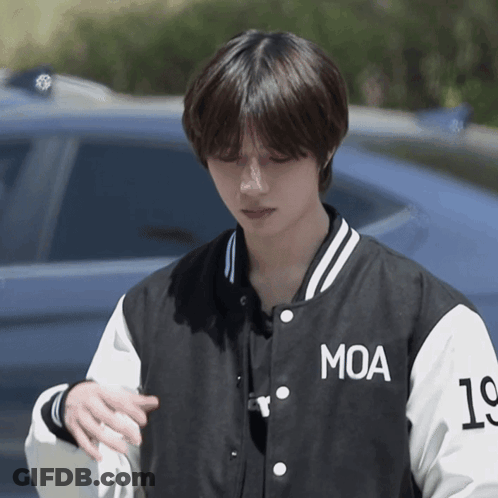 A Young Man Wearing A Black And White Moa Baseball Jacket GIF