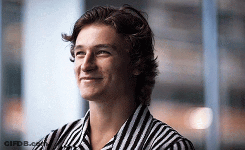 A Young Man Wearing A Black And White Striped Shirt Is Smiling GIF