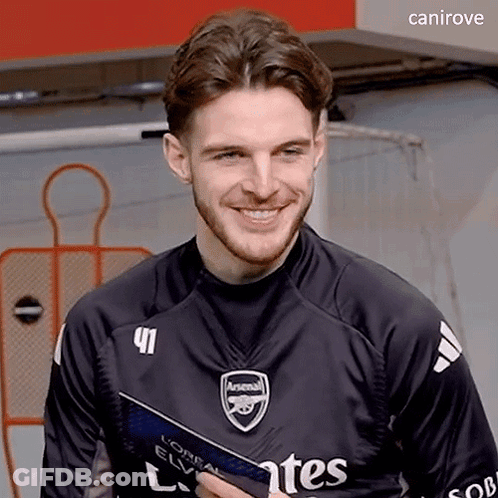 A Young Man Wearing A Black Arsenal Jersey Is Smiling . GIF