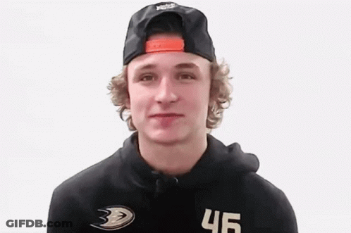A Young Man Wearing A Black Hat And A Black Hoodie Is Looking At The Camera . GIF