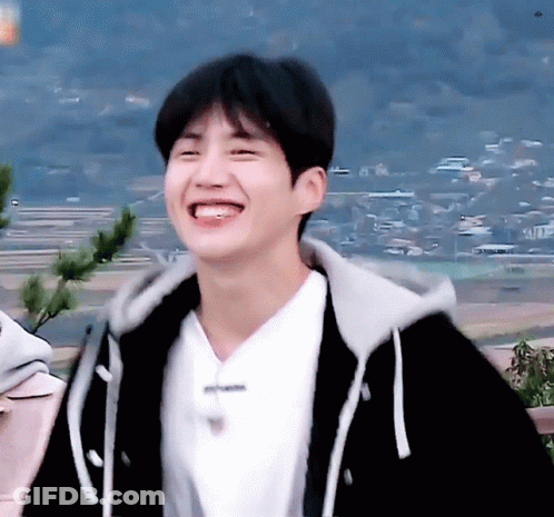 A Young Man Wearing A Black Hoodie And A White Shirt Smiles GIF