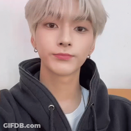 A Young Man Wearing A Black Hoodie And Earrings Is Looking At The Camera . GIF
