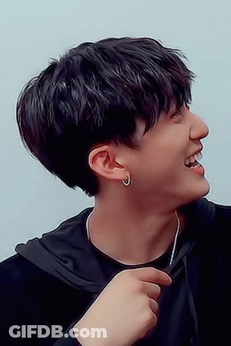 A Young Man Wearing A Black Hoodie And Earrings Smiles GIF