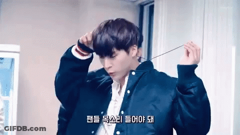 A Young Man Wearing A Black Jacket And A White Shirt Is Holding A String Around His Neck . GIF