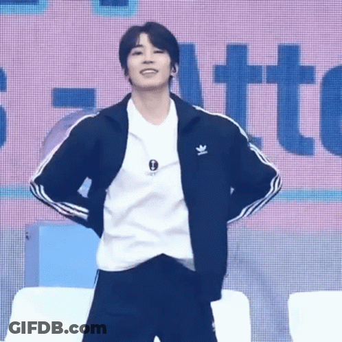 A Young Man Wearing A Black Jacket And A White Shirt Is Standing On A Stage . GIF
