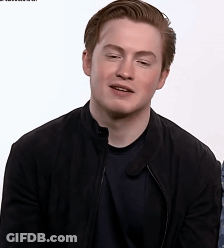 A Young Man Wearing A Black Jacket And Black Shirt Looks At The Camera GIF