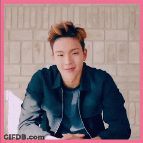A Young Man Wearing A Black Jacket Is Sitting In Front Of A Brick Wall . GIF