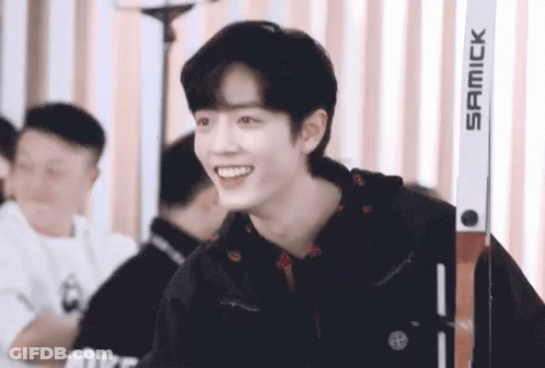 A Young Man Wearing A Black Jacket Is Smiling While Standing Next To A Pair Of Skis . GIF