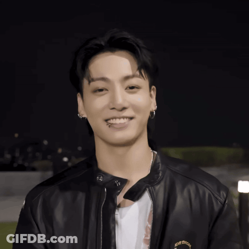 A Young Man Wearing A Black Leather Jacket And Earrings Smiles GIF