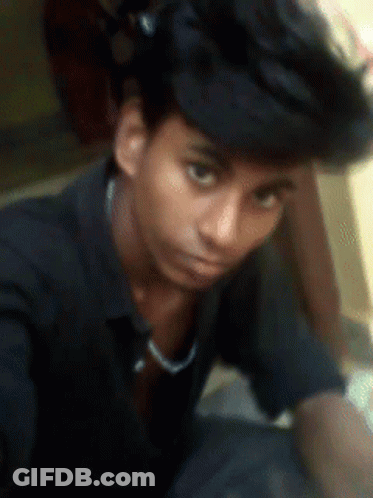 A Young Man Wearing A Black Shirt And A Black Hat Looks At The Camera GIF