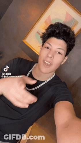 A Young Man Wearing A Black Shirt And A Necklace Is Taking A Selfie With A Tiktok Hashtag GIF