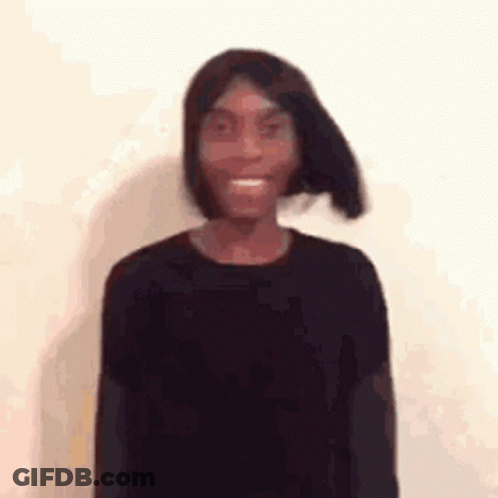 A Young Man Wearing A Black Shirt And A Wig Is Smiling . GIF