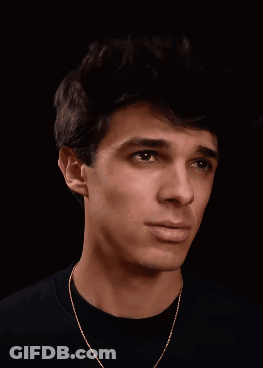 A Young Man Wearing A Black Shirt And Gold Chain Is Smiling GIF