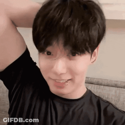 A Young Man Wearing A Black Shirt Is Smiling With His Arm Up GIF