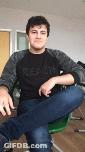 A Young Man Wearing A Black Shirt That Says Reach GIF
