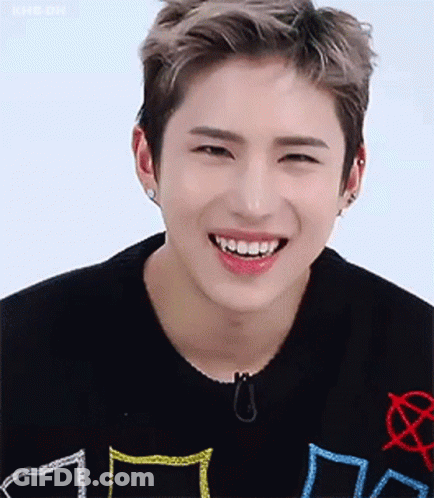 A Young Man Wearing A Black Sweater Is Smiling With His Teeth Showing . GIF