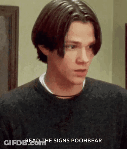 A Young Man Wearing A Black Sweater With The Words Read The Signs Poohbear Above Him GIF