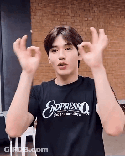 A Young Man Wearing A Black T-Shirt That Says Endpresso Is Making An Ok Sign With His Hands . GIF