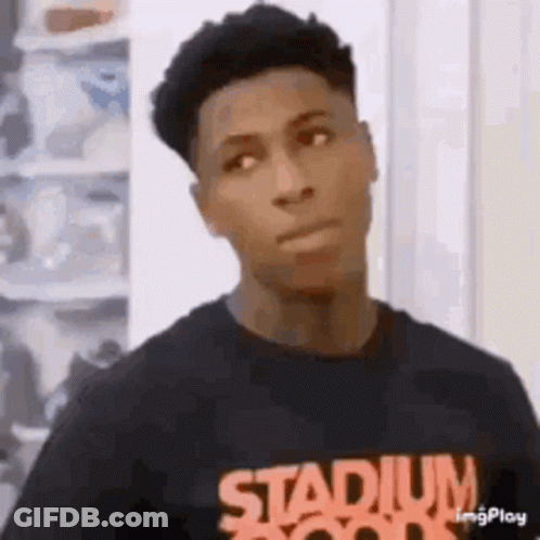 A Young Man Wearing A Black T-Shirt With The Word Stadium On It Is Standing In Front Of A Shoe Rack . GIF