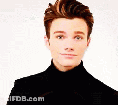 A Young Man Wearing A Black Turtleneck And A Black Jacket Is Making A Funny Face . GIF