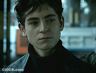 A Young Man Wearing A Black Turtleneck And A Black Leather Jacket Looks At The Camera GIF