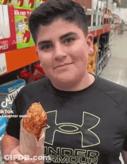 A Young Man Wearing A Black Under Armour Shirt Is Holding A Fried Chicken Wing In A Paper Bag . GIF