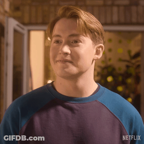 A Young Man Wearing A Blue And Purple Sweater With A Netflix Logo On The Back . GIF