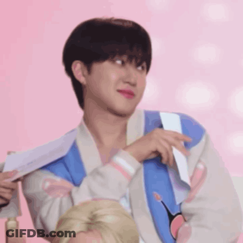 A Young Man Wearing A Blue And White Jacket Is Holding A Piece Of Paper . GIF