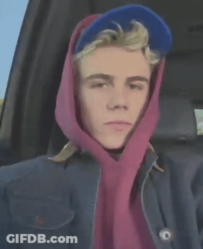 A Young Man Wearing A Blue Hat And A Pink Scarf Around His Head GIF