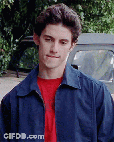 A Young Man Wearing A Blue Jacket And A Red T-Shirt Is Standing In Front Of A Truck GIF