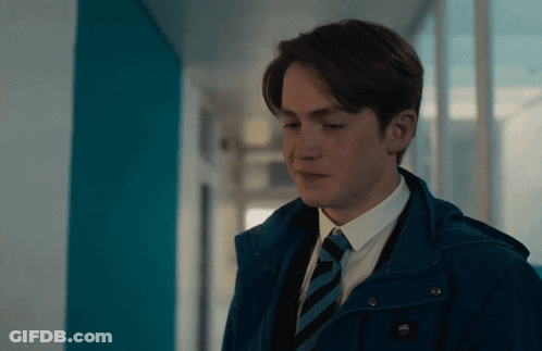 A Young Man Wearing A Blue Jacket And Tie With The Word Vans On It GIF