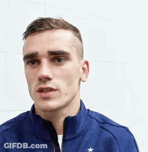A Young Man Wearing A Blue Jacket With A Star On It Is Standing In Front Of A White Wall . GIF