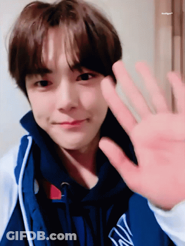 A Young Man Wearing A Blue Jacket With The Letter W On It Waves His Hand GIF